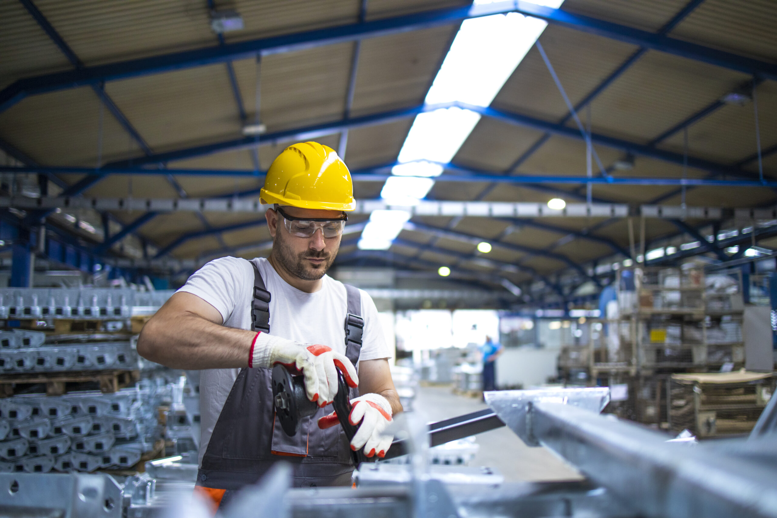 Factory worker working in industrial production hall.